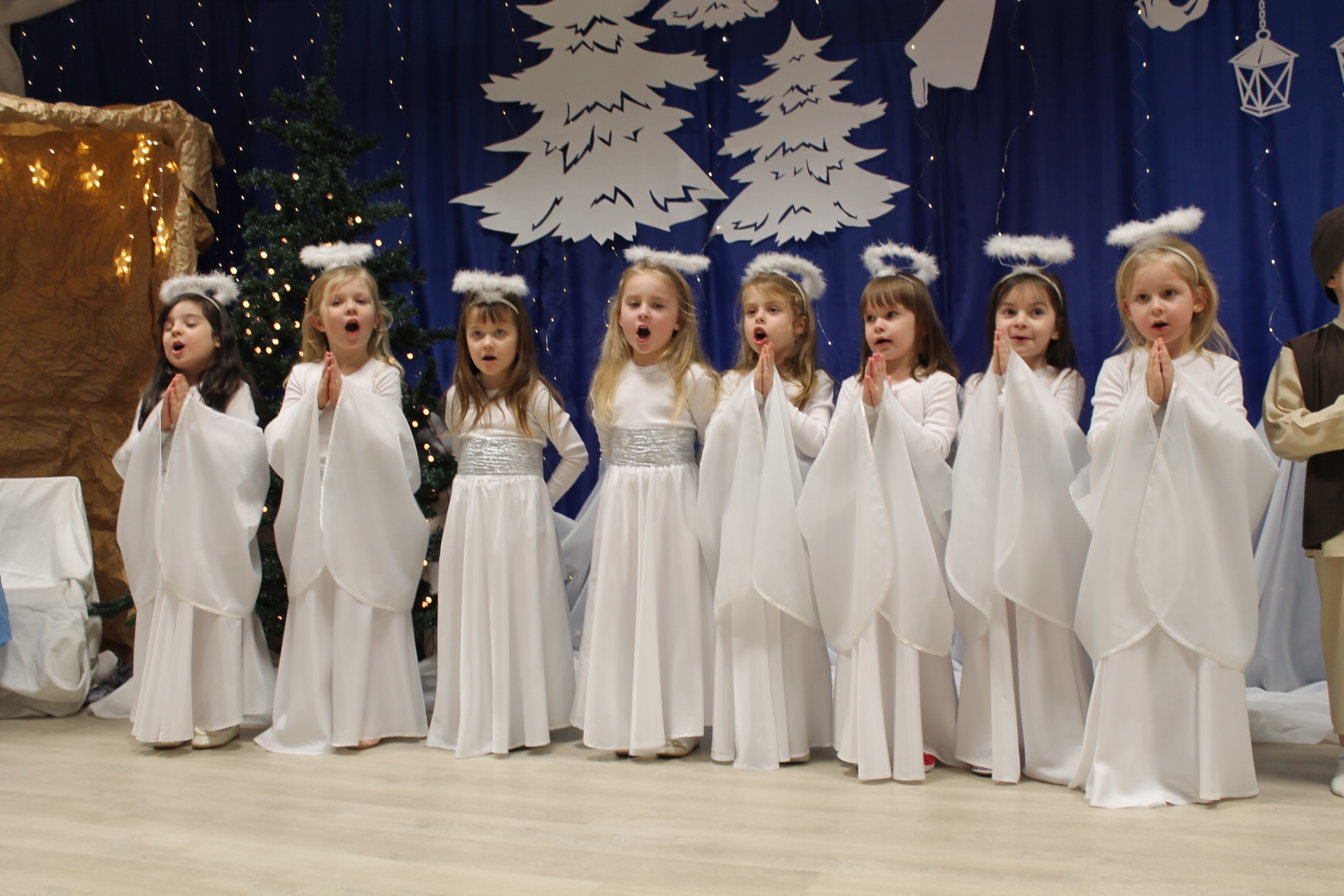 Dziewczynki w kostiumach aniołków na tle zimowej dekracji
