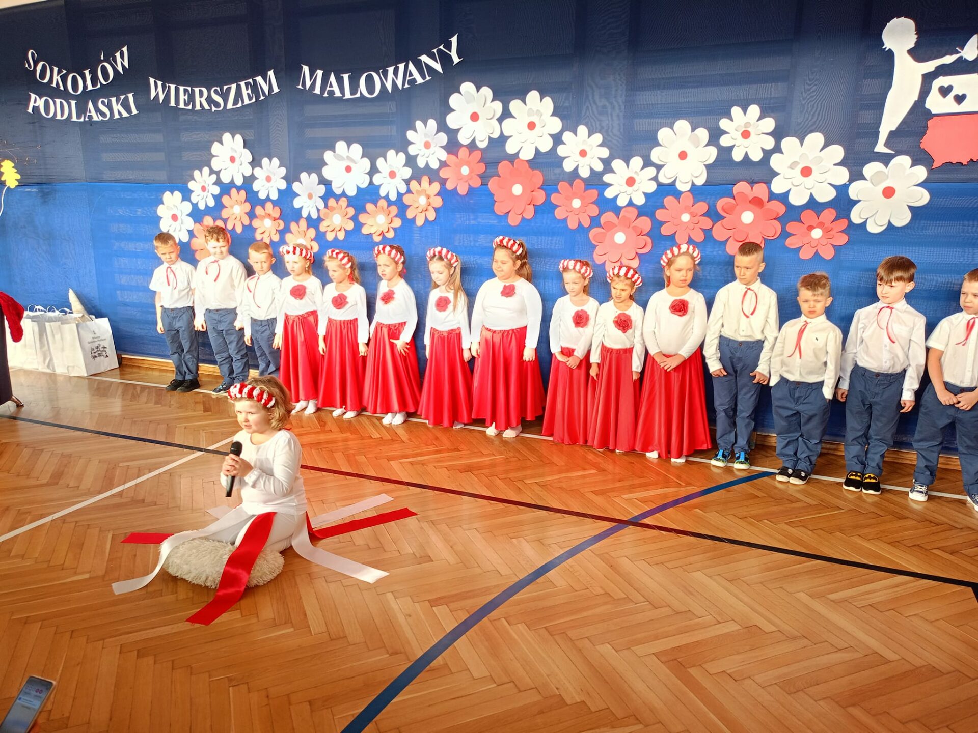 Występ 6-latków z grupy "Misie". W tle dekoracja z papierowych kwiatów.