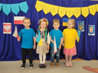 Dzieci z flagami na tle ścianki a polskimi i ukraińskimi symbolami narodowymi