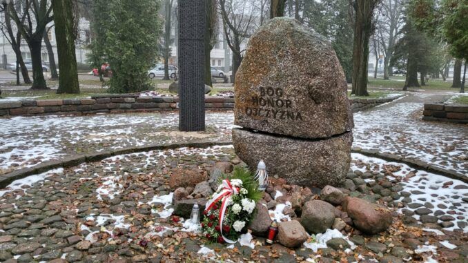 Centralny kamień Pomnika Czynu Niepodległościowego. Pod nim kwiaty i znicze.