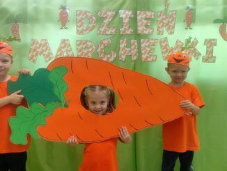 przedszkolaki ubrane na pomarańczowo trzymają marchewkę z papieru
