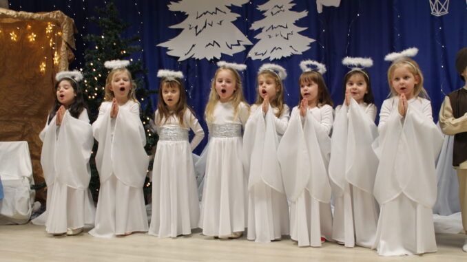 Dziewczynki w kostiumach aniołków na tle zimowej dekracji