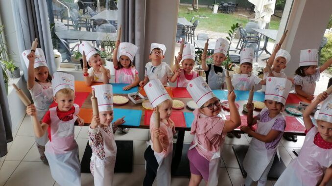"Misie" i "Smerfy" w pizzerii Da Grasso. Dzieci ubrane w fartuszki, na głowach czepki szefa kuchni, w rękach wałki do ciasta.