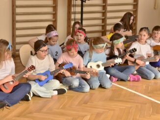 Grupa dziewcząt grająca na ukulele na sali gimnastycznej