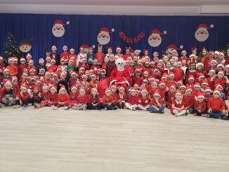 Wspólne zdjęcie wszystkich dzieci z Mikołajem. W tle mikołajkowa dekoracja.