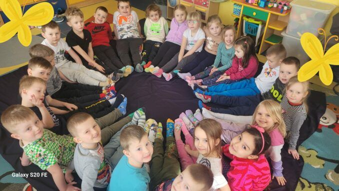 przedszkolaki w kóeczku na podłodze, demonstrują kolorowe skarpetki nie do pary