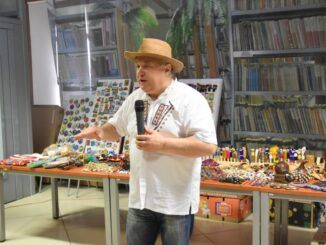Ryszard Sobolewski w kapeluszu z szerokim rondem, przemawia do uczestników spotkania.
