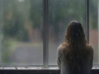 Jesień - grafika ilustracyjna. Kobieta stoi w oknie, za którym pada deszcz.