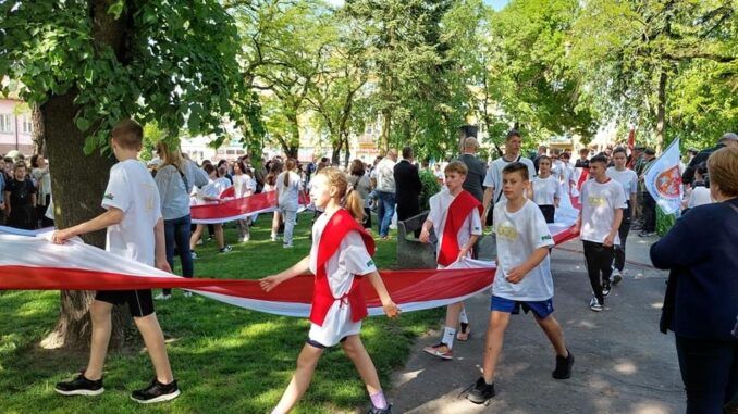 uczestnicy Sztafety Niepodległości podczas przemarszu z biało-czerwoną flagą na Skwerze Księdza Brzóski
