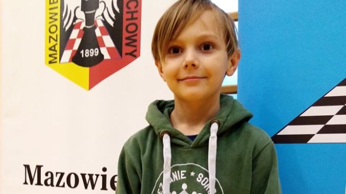 Mateusz Strus na tle logo Polskiego Związku Szachowego